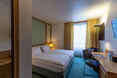 a hotel room with a bed and a desk at Arthotel ANA Aura in Aystetten