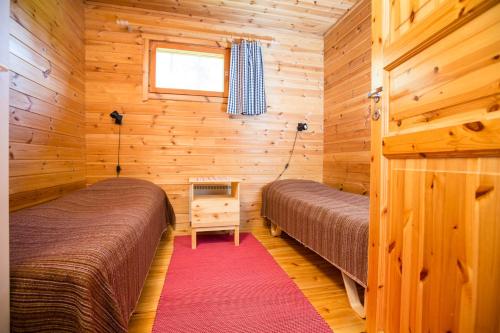 a bedroom with two beds in a wooden cabin at Resort Naaranlahti in Punkaharju