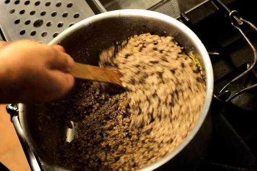 a person stirring food in a pot with a wooden spoon at Relais La Torre in Chiassa Superiore