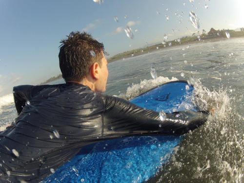 a man riding on a surfboard in the water at THE NYAMO surf & stay in Pulukan