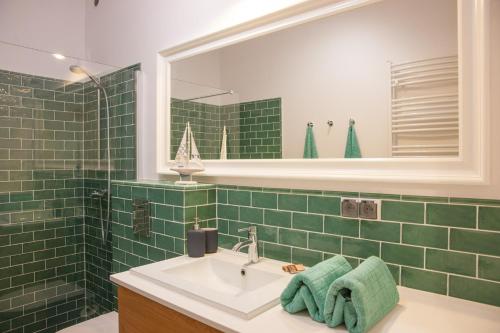 W wyłożonej zielonymi kafelkami łazience znajduje się umywalka i lustro. w obiekcie Apartament Villa Nautica w Rydzewie