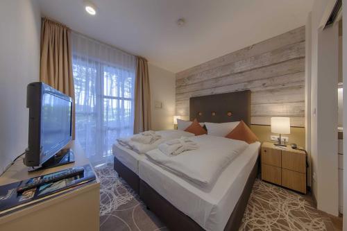 a bedroom with a large bed and a flat screen tv at Aquamaris Strandresidenz Rügen in Juliusruh