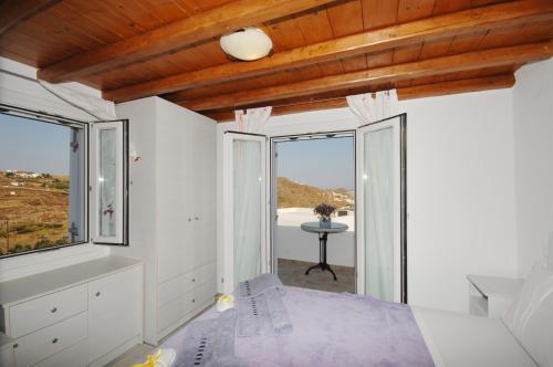 a bedroom with a bed and large windows at Lino Apartments in Paradise Beach