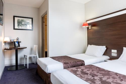 a hotel room with two beds and a desk at Hôtel des Reignaux in Lille