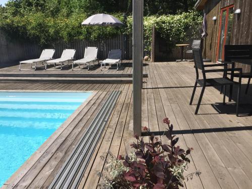 a deck with chairs and an umbrella and a pool at Bodelssons by the Sea in Tosteberga