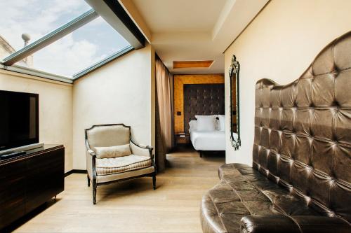 a room with a couch and a tv and a bedroom at Hotel Bagués, a Small Luxury Hotel of the World in Barcelona