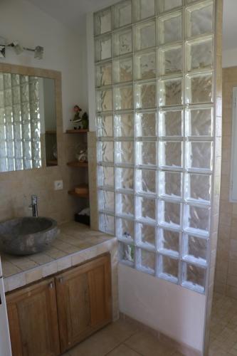 La salle de bains est pourvue d'un lavabo et d'une paroi en verre. dans l'établissement Charmante maison de village, à Cucuron