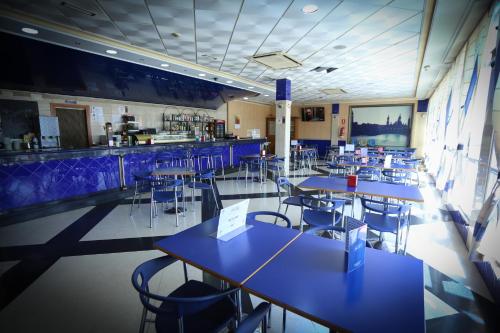 a restaurant with blue tables and chairs and a bar at Hotel El Cisne in Zaragoza