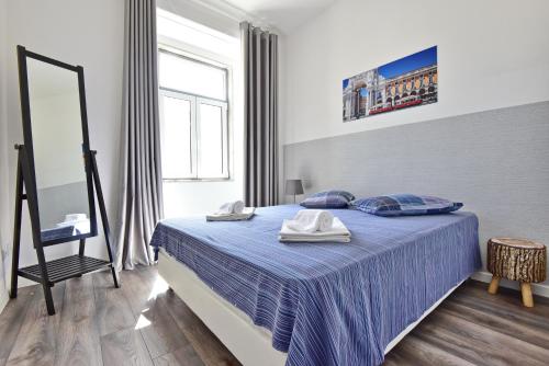 a bedroom with a blue bed with a mirror and a chair at TryLisbon Calvário in Lisbon