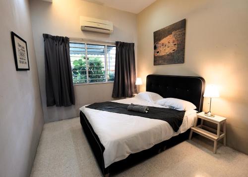 een slaapkamer met een bed met een zwart hoofdeinde en een raam bij Fivehouz Guest House in Petaling Jaya