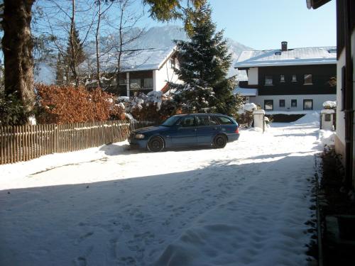 a car parked in front of a house in the snow at Haus Alpenrose in Schwangau