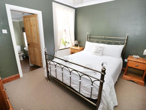 a bedroom with a bed with white sheets and a window at Rose Cottage in Great Yarmouth