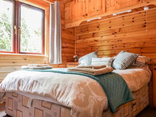 a bedroom with a bed in a log cabin at Oak Lodge in Falmouth