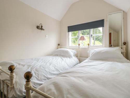 two beds in a white room with a window at Lilac Cottage in Great Malvern