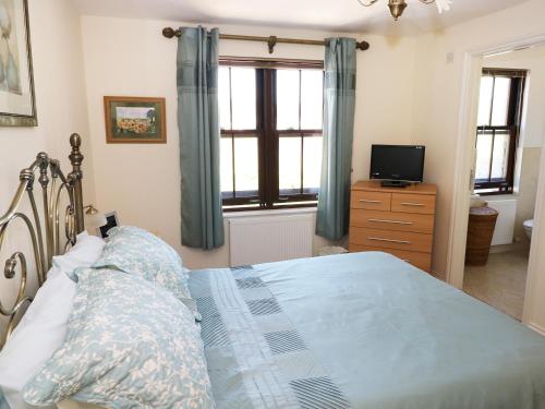 a bedroom with a bed and a television in it at 5 Chandlers Yard in Burry Port