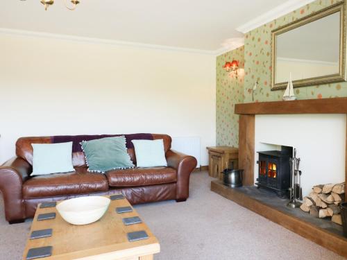 a living room with a leather couch and a fireplace at Westhaven in Mallaig
