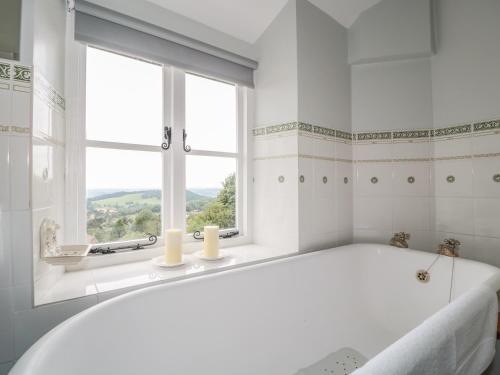 a white bathroom with a tub and a window at Lilac Cottage in Great Malvern