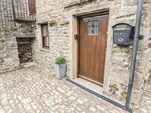 a stone building with a wooden door and a plant at Heugh Barn in Thwaite