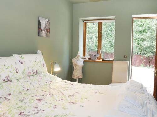 a bedroom with a bed and a window at Woodpecker Cottage in Ludlow