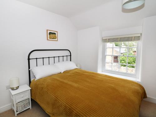 a white bedroom with a bed and a window at Gritstone Cottage in Bakewell