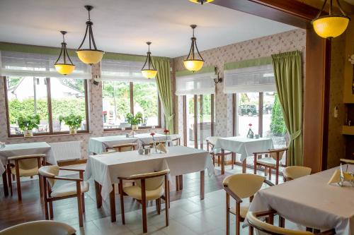 a restaurant with white tables and chairs and windows at Villa Mariner in Mielno