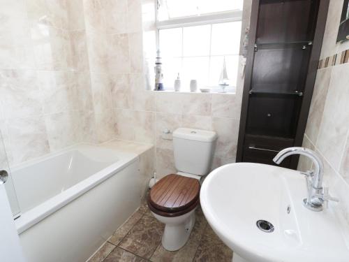 a bathroom with a toilet and a tub and a sink at West Shore Cottage in Llandudno