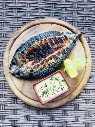 a fish on a wooden plate with a dish of cheese at Dikii Med in Geletintsy