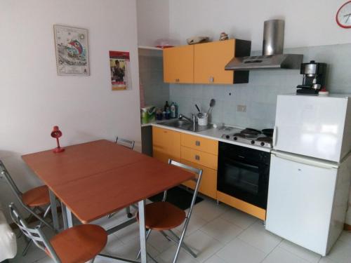 Il comprend une cuisine équipée d'une table en bois et d'un réfrigérateur blanc. dans l'établissement Monolocale Stella, à San Benedetto del Tronto