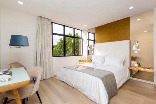 1 dormitorio con cama, mesa y escritorio en The Office Guest en Guimarães