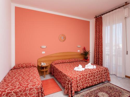 a hotel room with two beds and a window at Hotel Bahama in Rimini