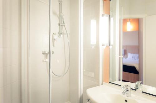een witte badkamer met een douche en een wastafel bij ibis Grenoble Gare in Grenoble