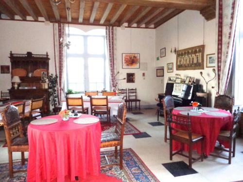a dining room with red tables and chairs and a piano at Château d'Avanton in Avanton