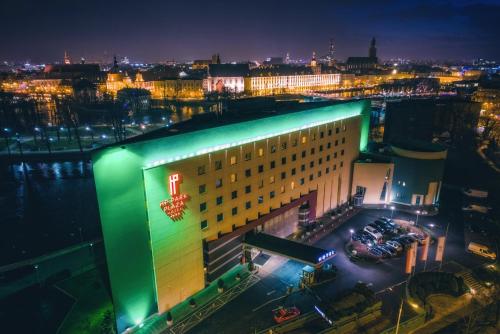een groot gebouw met 's nachts groen licht bij HP Park Plaza in Wrocław