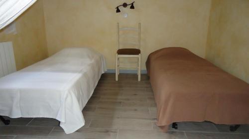 two beds in a room with a chair and a ladder at Joëlle et Daniel in Entrevaux
