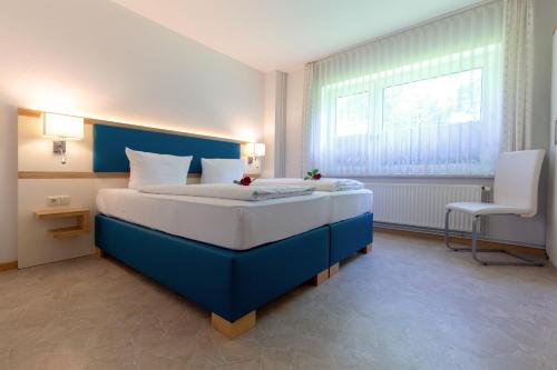 a bedroom with a blue and white bed and a chair at Haus Hafeneck mit Frühstücksoption in Bensersiel