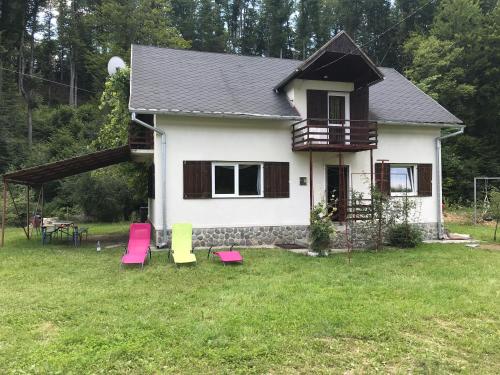 a house with pink and green chairs in the yard at Complex Adela Transfăgărășan in Cîrţişoara