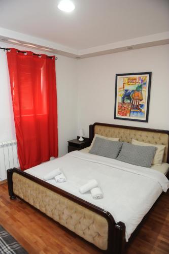 1 dormitorio con 1 cama grande y cortina roja en Apartments Erakovic en Nikšić