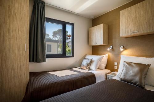 een hotelkamer met 2 bedden en een raam bij Padova Premium Camping Resort by Valamar in Rab