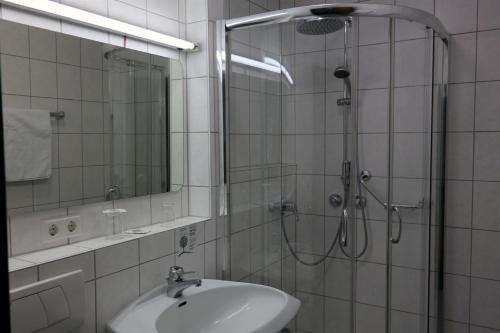 a bathroom with a shower and a sink and a mirror at Alpenhotel Gastager in Inzell