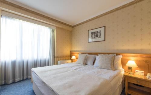 a bedroom with a large white bed and a window at Hotel Downtown in Sofia