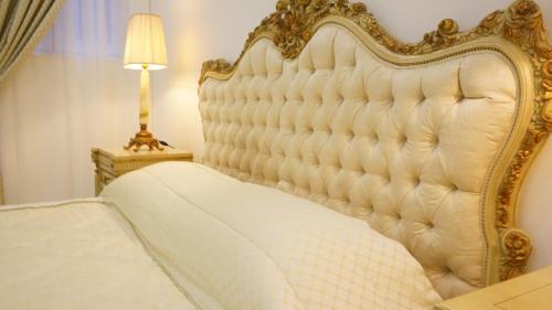 a white bed with a gold frame next to a lamp at Ivory Suite Valletta in Valletta