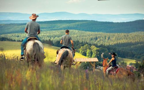 grupa ludzi jeżdżących konno na polu w obiekcie Gryglówka w Zieleńcu