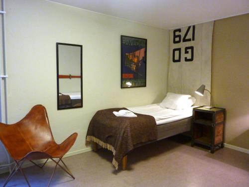 ein Schlafzimmer mit einem Bett, einem Stuhl und einem Spiegel in der Unterkunft Norrqvarn Hotell in Lyrestad
