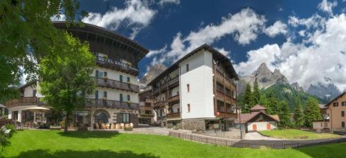 un hôtel dans les montagnes avec une pelouse verdoyante dans l'établissement Hotel Garni Suisse, à San Martino di Castrozza