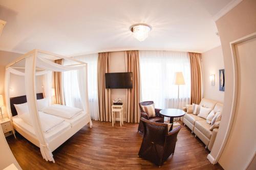 a living room with a bed and a couch at HIRSCH 1783 Hotel LANDHAUS in Langenargen
