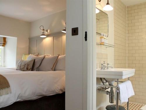 uma casa de banho com uma cama e um lavatório num quarto em The Plough Inn em Little Faringdon