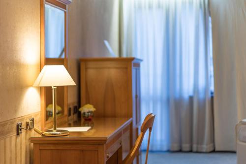 a room with a desk with a lamp and a mirror at Hotel Downtown in Sofia