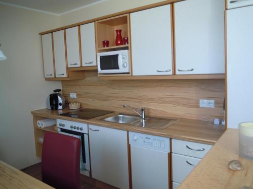 eine Küche mit weißen Schränken, einer Spüle und einer Mikrowelle in der Unterkunft Ferienwohnung Lackner-Krabath in Tamsweg