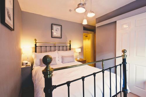 a bedroom with a bed with white sheets and a railing at Rum Doodle, Windermere B&B in Windermere