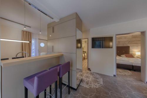 a kitchen with purple bar stools and a bedroom at Aquamaris Strandresidenz Rügen in Juliusruh